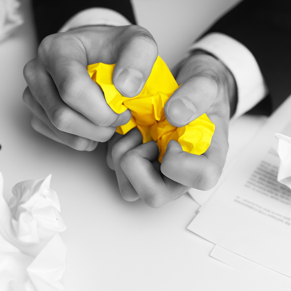 Hands holding crumpled yellow paper representing thy most year-end deals fair.